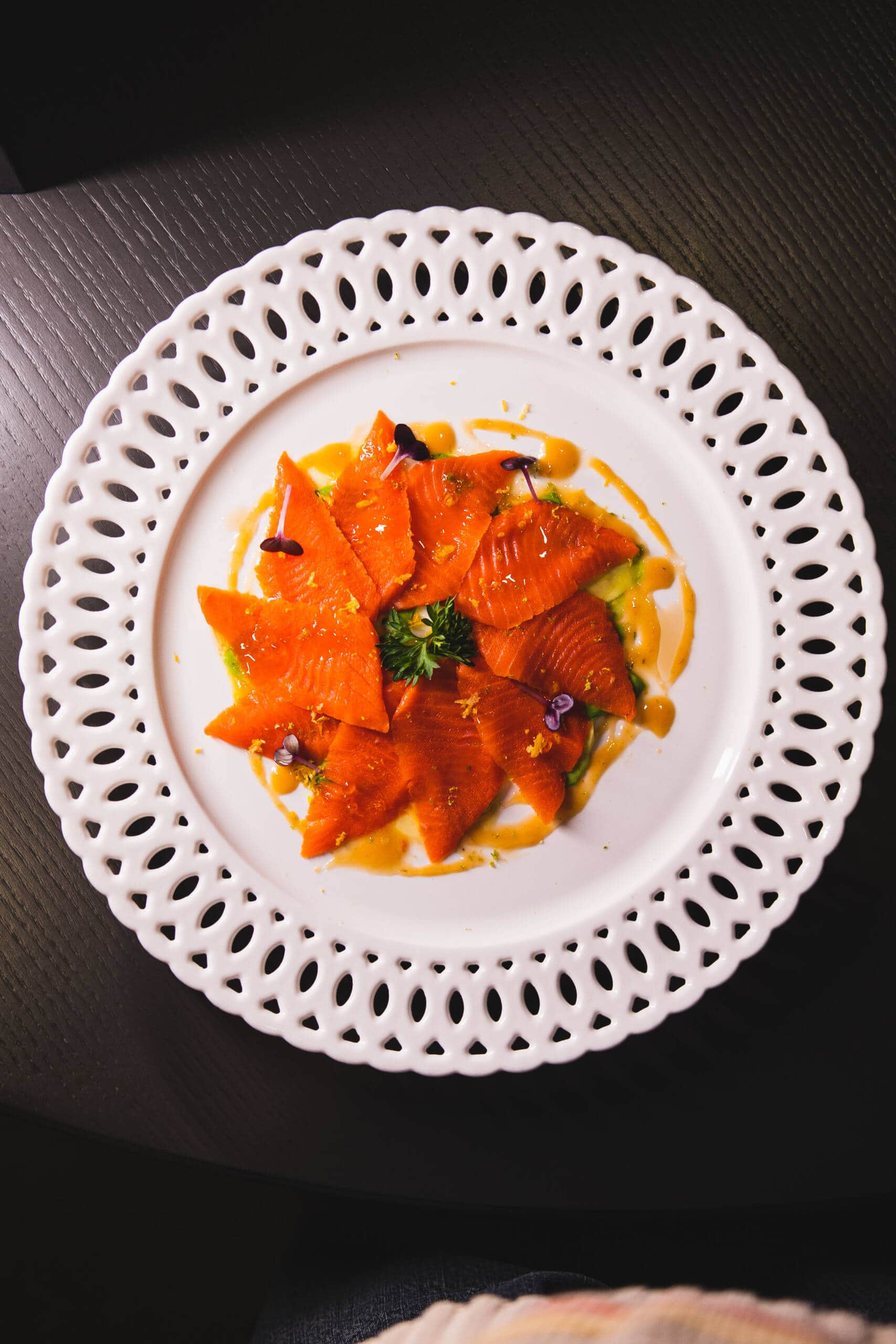 Piatti di salmone affumicato decorato con erbe e fiori commestibili.
