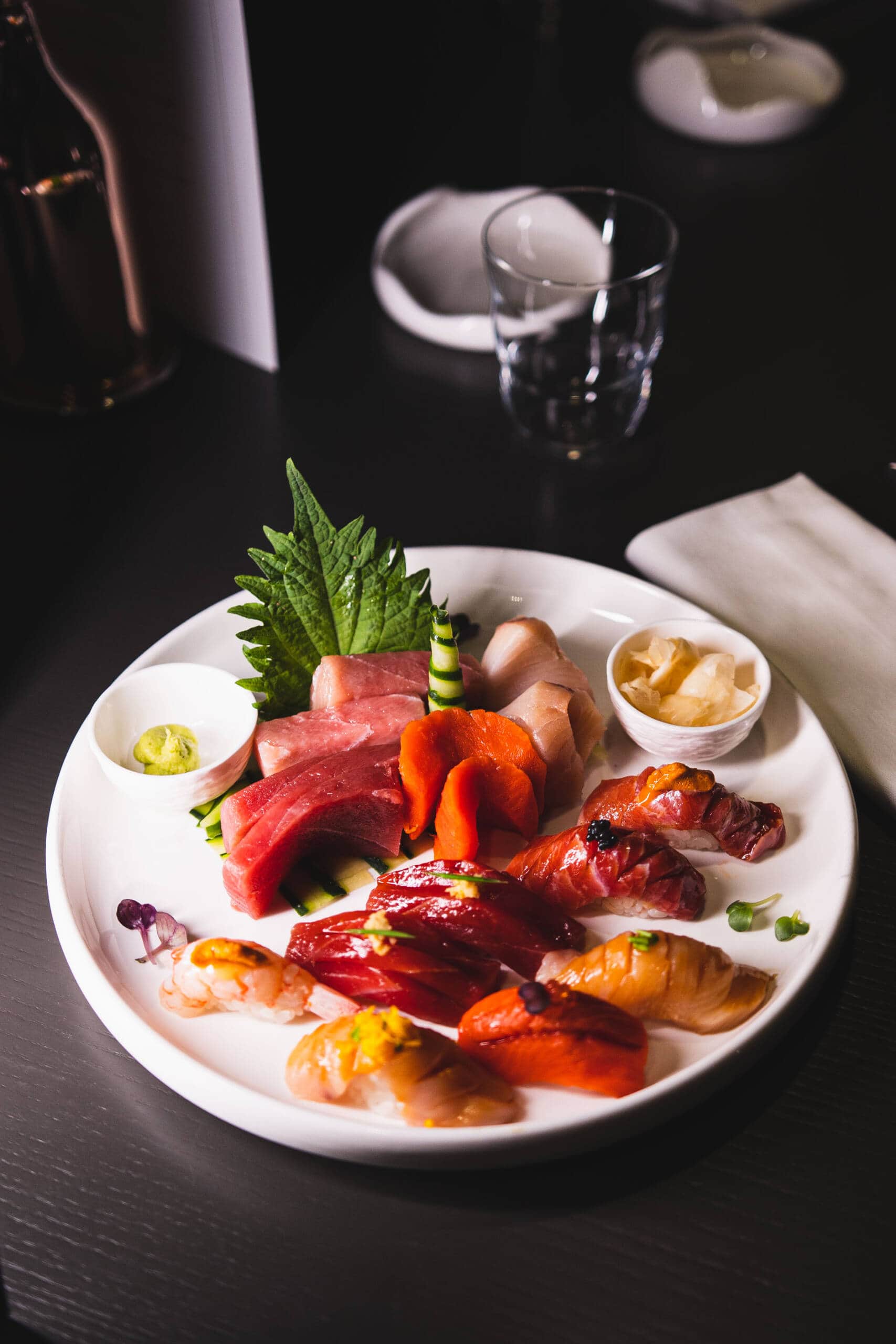 Piatti di sashimi e sushi con wasabi e zenzero su piatto bianco.