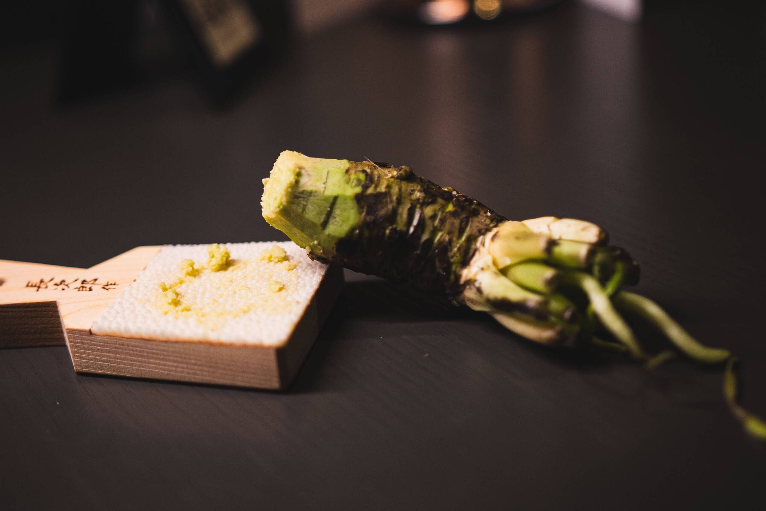 Wasabi fresco e wasabi in pasta su un tavolo scuro.