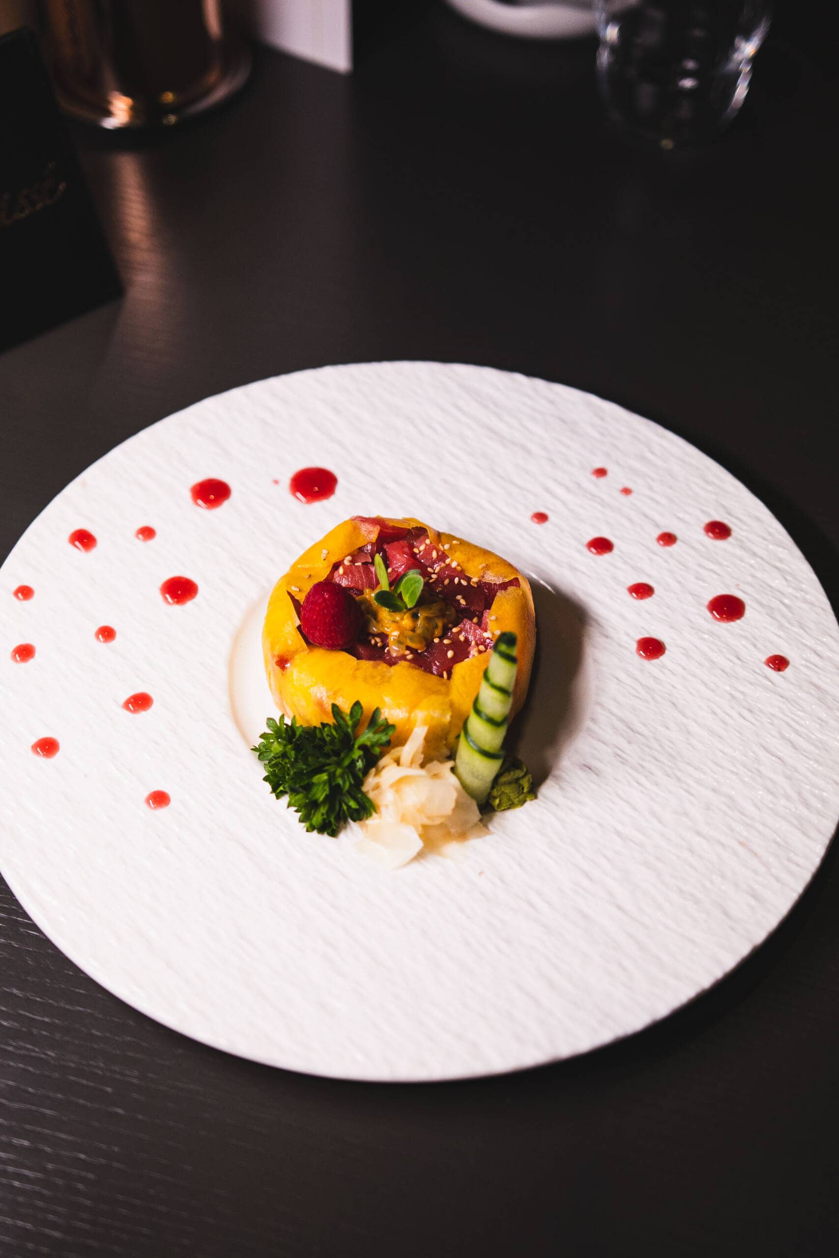 Piattino gourmet con frutta, verdure e decorazioni eleganti.